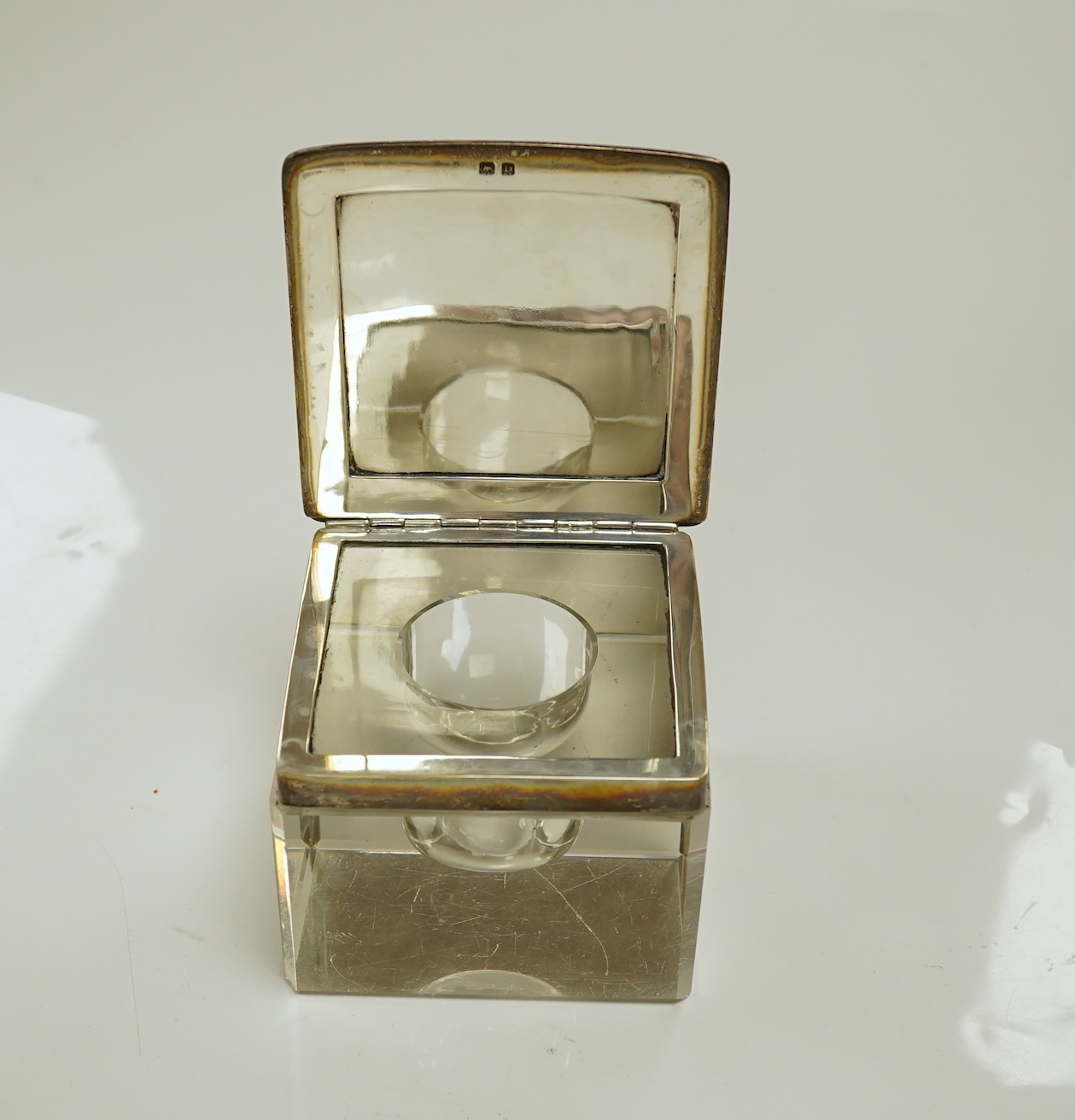 A George V silver lidded glass square inkwell, by Henry Matthews, Birmingham, 1929, width 95mm. Condition - poor to fair